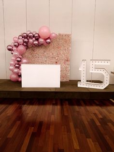 a room with wooden floors and balloons on the wall, including a sign that says 5