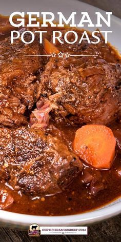 a white bowl filled with stew and carrots on top of a wooden table next to a