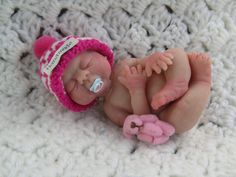 a newborn baby is wearing a pink hat and laying on it's side next to a teddy bear