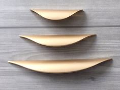 three gold spoons sitting next to each other on a wooden surface with wood grain