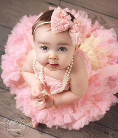 a baby girl wearing a pink dress and pearls