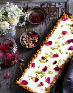 a cake with white frosting and flowers on it next to bowls of dried flowers