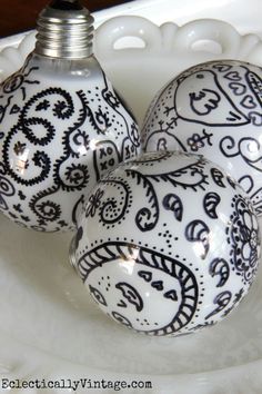 three white and black ornaments sitting on top of a white plate with a light bulb in the middle