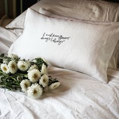 a bouquet of daisies on a bed with a pillow that says i love you always