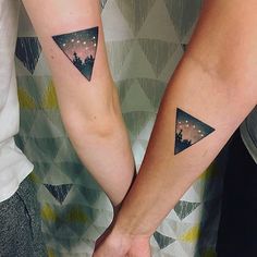 two people with matching tattoos on their arms and one is holding the other's hand