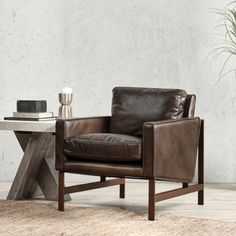 a brown leather chair sitting on top of a rug next to a wooden table and potted plant