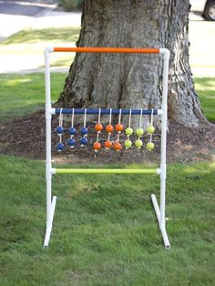 an outdoor game set up in front of a tree with balls and sticks on it