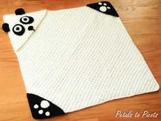 a crocheted panda bear rug is laying on the floor next to a wooden floor