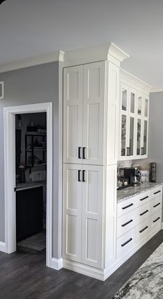 a kitchen with white cupboards and marble counter tops in the middle of the room