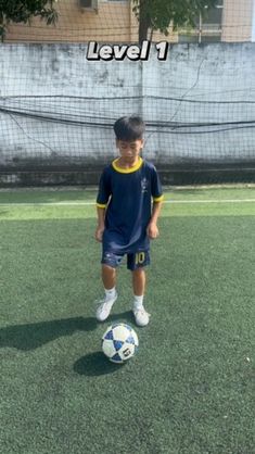 a young boy standing in front of a soccer ball