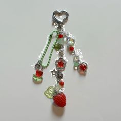 a key chain with charms attached to it on a white surface, including a strawberry