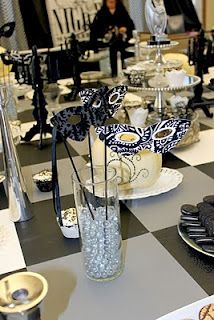 a black and white checkered table cloth with cookies on it, silverware, and glass vases