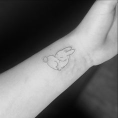 a small tattoo on the wrist of a person's arm with an outline of a bunny