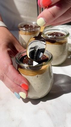 two jars filled with different types of desserts on top of a white tablecloth