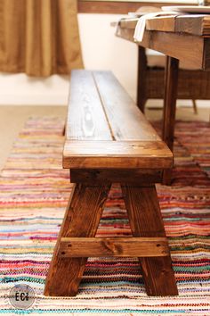 a wooden bench sitting on top of a colorful rug