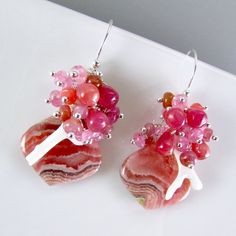 I love these focals! They are Argentine rhodochrosite gems and measure 22x20mm. They have been wrapped in sterling silver wire and dangle below a gorgeous combination of smooth ruby briolettes, pink moonstone, pink sapphire, white branch coral. Each bead is meticulously wrapped onto it's own head pin. The entire cluster is topped. I have used simple sterling ear wires. The earrings measure 1 3/4 (44mm.) from the top of the ear wires. Unique Pink Sterling Silver Earrings, Pink Cabochon Earrings As Gift, Pink Cabochon Earrings For Gift, Unique Pink Gemstone Earrings, Sterling Silver Pink Wire Wrapped Earrings, Pink Sterling Silver Wire Wrapped Earrings, Black Freshwater Pearls, Pink Moonstone, Gold Chandelier Earrings