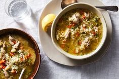 two bowls of soup on a table next to a glass of water and spoons