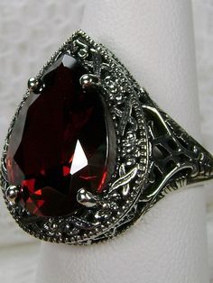 Red Garnet CZ Gemstone Teardrop RingTear Vic Design#D28 Inspired by Victorian and Art Deco designs, this high-quality filigree ring is handcrafted in sterling silver. This teardrop ring is set with an 8 carat pear cut flawless red CZ (Cubic Zirconia) gemstone. The gem is 16mm (~5/8") x 12mm (~1/2"). The gorgeous stone has a lovely vibrant color. The inside of the band is marked 925 for sterling silver. Notice the beautiful filigree of the silver setting. This is a ring with beauty and grace. The Formal Red Pear-shaped Ruby Ring, Formal Pear-shaped Ruby Ring, Formal Pear-shaped Ruby Jewelry, Formal Teardrop Ruby Ring, Ornate Teardrop Jewelry With Intricate Design, Elegant Pear-shaped Ruby Jewelry, Elegant Party Ruby Ring, Classic Teardrop Ruby Ring For Formal Occasions, Elegant Garnet Filigree Ring For Wedding