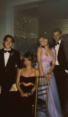 a group of people standing next to each other in formal wear and tuxedos