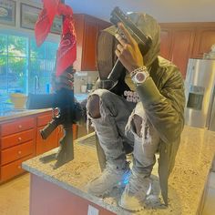 a man sitting on top of a counter next to a pair of jeans and shoes