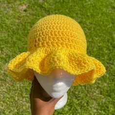 a child's yellow crocheted hat on top of a white mannequin head