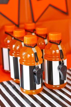 orange and black striped water bottles are sitting on a table with an orange wall in the background