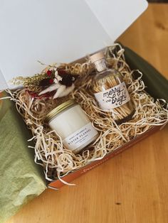 an open gift box containing two bottles of booze and marshmallows on a wooden table