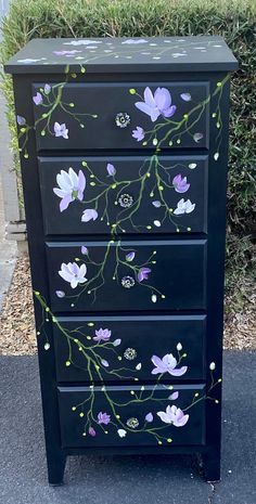 a black dresser with purple flowers painted on it