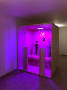 an empty room with purple lighting in the corner and two saunages on the floor