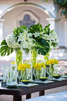 a table topped with vases filled with flowers and greenery