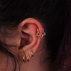 a woman's ear with two small gold hoops