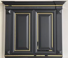 a black cabinet with gold trim on the doors and bottom panel is shown in this image