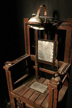 an old wooden chair with a mirror on the back and a light hanging above it