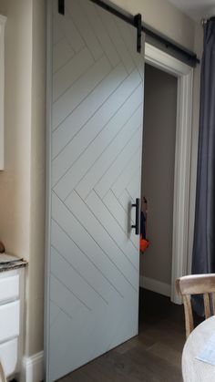 an open sliding door in a kitchen next to a dining room table and white cabinets