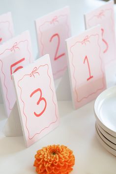 the table numbers have been placed on top of each other and are decorated with an orange flower