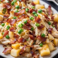 a white plate topped with pasta and meat covered in cheese, peas and bacon next to a fork