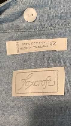 a label on the back of a blue jean jacket that says, 100 % cotton made in thailand