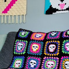 a crocheted skull pillow on a couch in front of two wall hangings