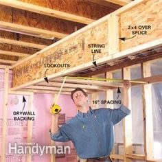 a man is working on the framing of a house with his hands holding a screwdriver