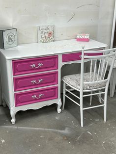 a white desk with pink drawers and a chair next to it on concrete flooring