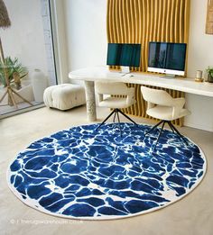 a blue and white rug in front of a desk with two computer monitors on it