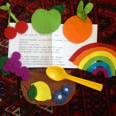 an open book with felt fruit and rainbows on the pages, next to a spoon