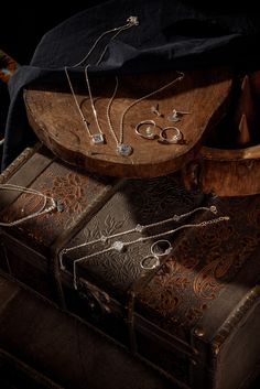 an assortment of jewelry sitting on top of a wooden box next to a black cloth