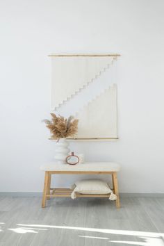 a white room with a bench, plant and rug on the floor in front of it