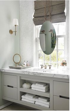 a bathroom with two sinks, mirrors and towels on the shelf in front of it