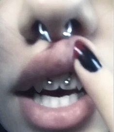 a close up of a person with black and white nails on her nose, holding onto the lip of another person's mouth