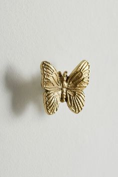 a gold butterfly brooch sitting on top of a white wall