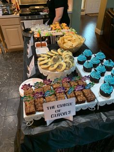 a buffet table filled with cupcakes, cookies and desserts for people to eat