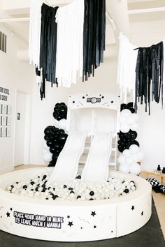 a room decorated in black and white with balloons, streamers, and a slide