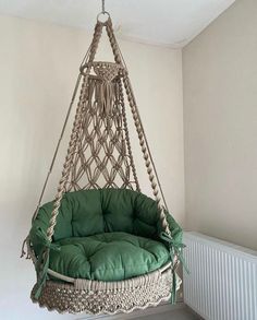 a hanging chair in the corner of a room with a green cushion on top of it